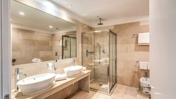 A modern bathroom with two sinks, a large mirror, and a glass-enclosed shower.