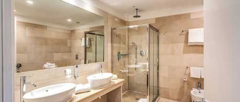 A modern bathroom with two sinks, a large mirror, and a glass-enclosed shower.