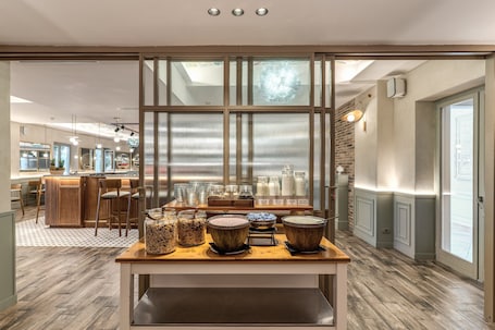 A modern kitchen with a breakfast bar, wooden flooring, and a view through a glass partition.. Hotel Isola Sacra Rome Airport
