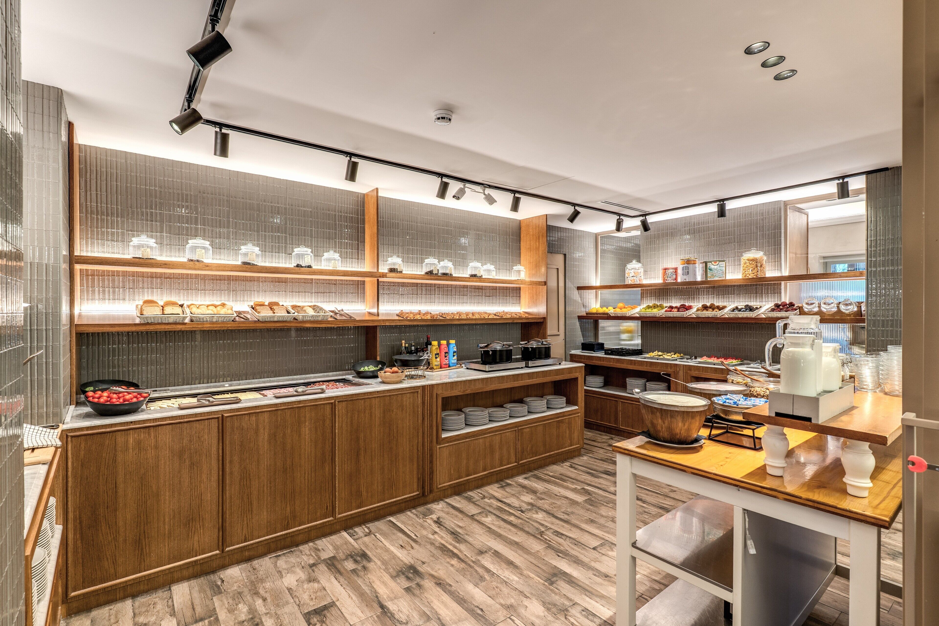 A modern breakfast bar with wooden cabinets, glass display cases, and a variety of food items.