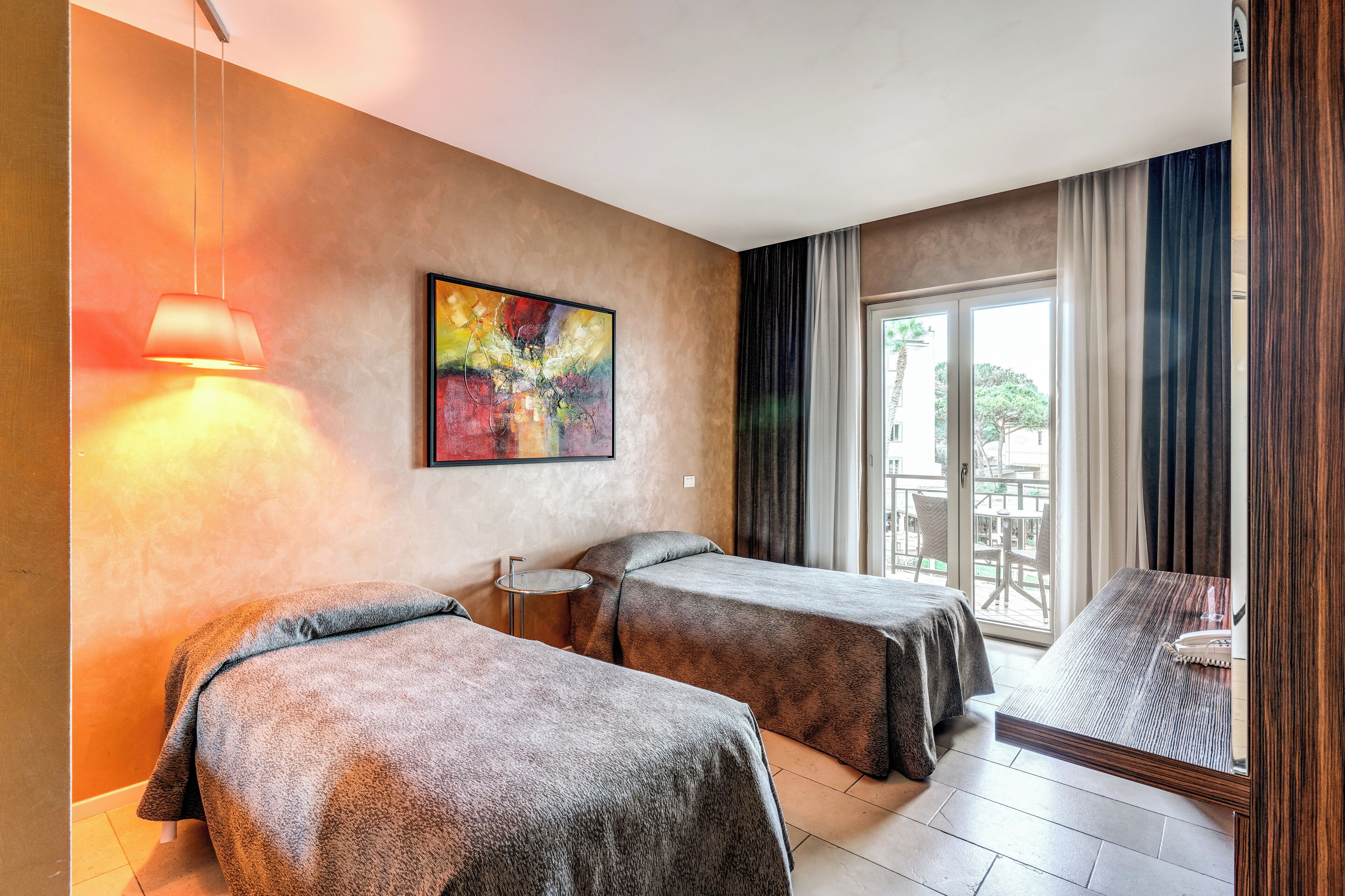 Habitación de hotel con dos camas, un cuadro en la pared, una ventana con cortinas y vistas al exterior.