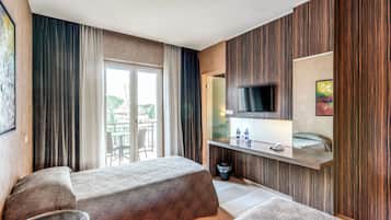 Una habitación de hotel con cama, escritorio, televisor y vistas al exterior.
