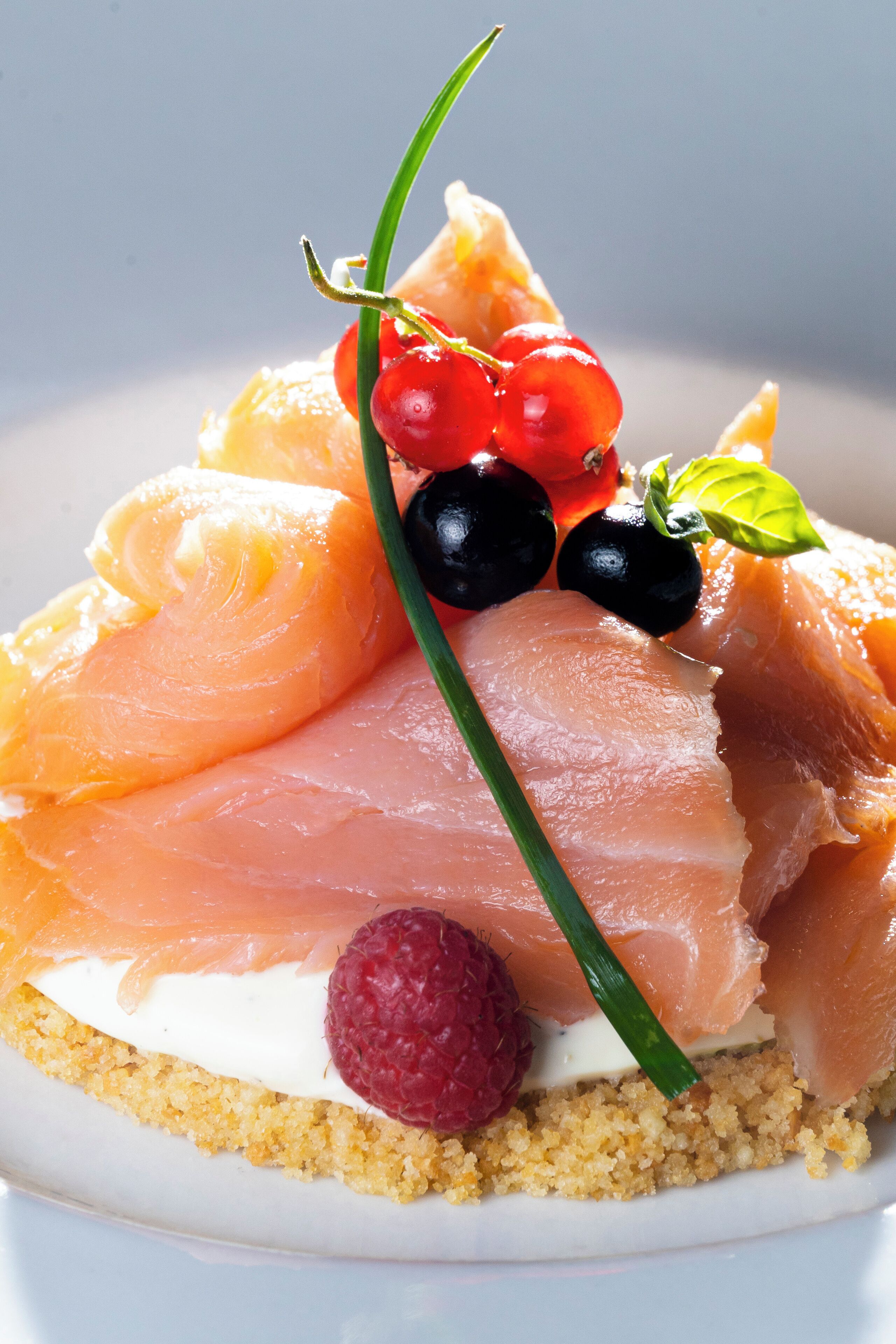 A dessert with salmon, berries, and a green garnish on a plate.