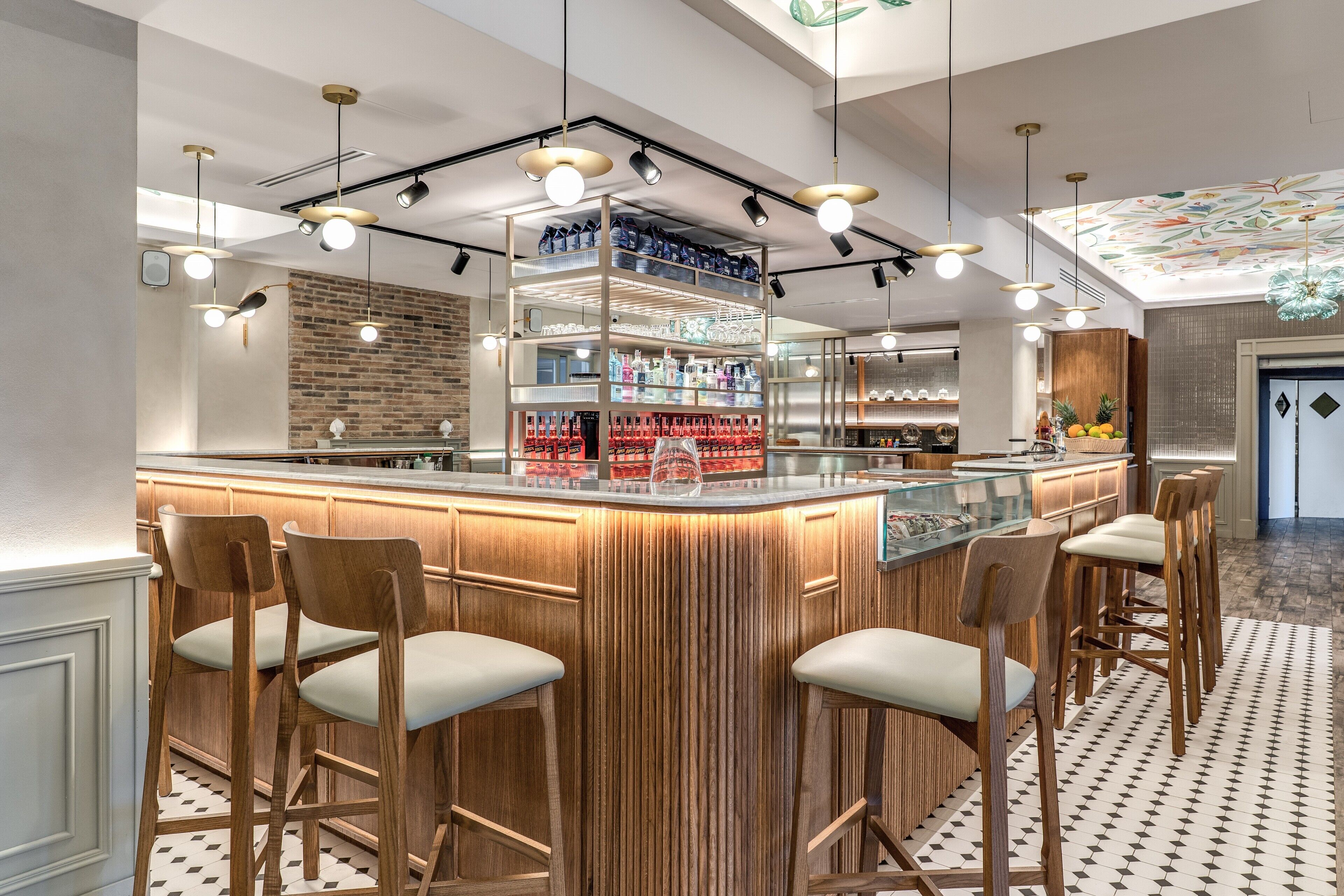 Un espace bar avec des tabourets de bar en bois, un comptoir central et un éclairage suspendu.