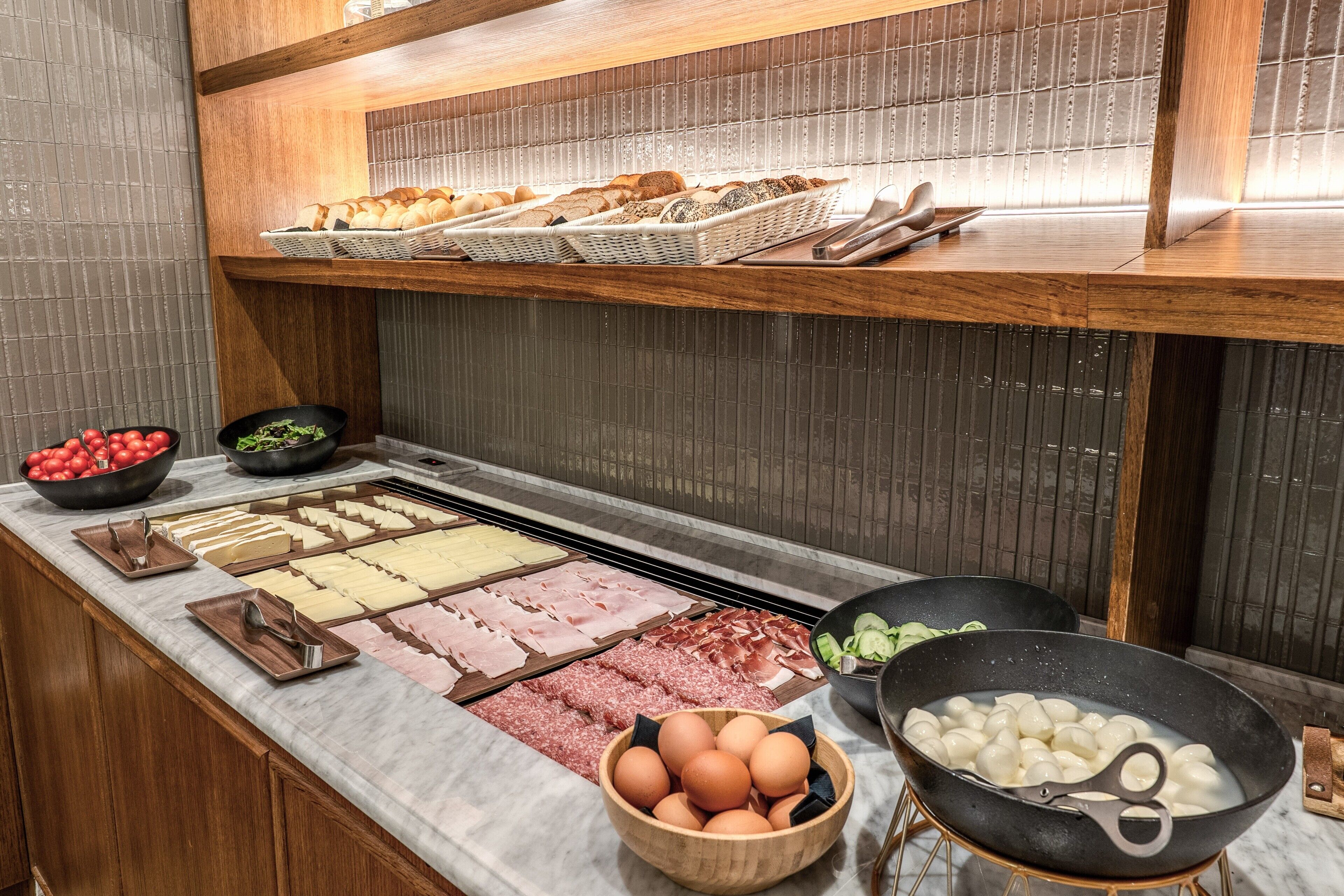 A buffet with various food items including meats, cheeses, and eggs.