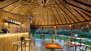 An outdoor dining area with bamboo walls, wooden tables, and chairs.