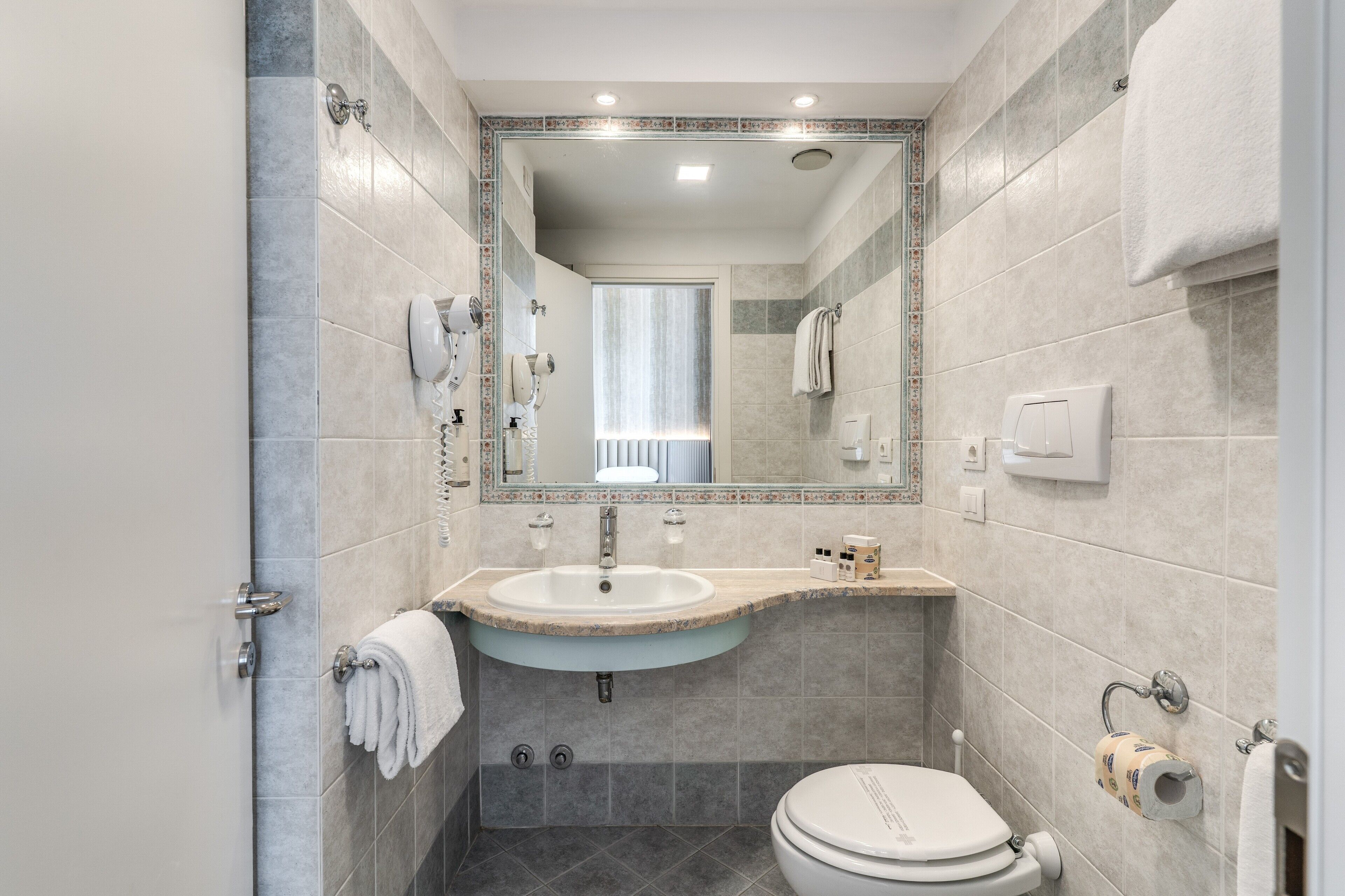 Une salle de bain moderne avec un lavabo, des toilettes et un grand miroir.