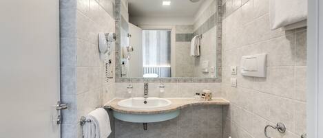 Un baño moderno con lavamanos, inodoro y un espejo grande.