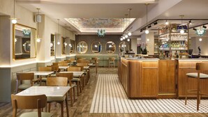 A restaurant with wooden tables and chairs, a bar area, and a ceiling with a floral pattern. - Hotel Isola Sacra Rome Airport (Fiumicino)