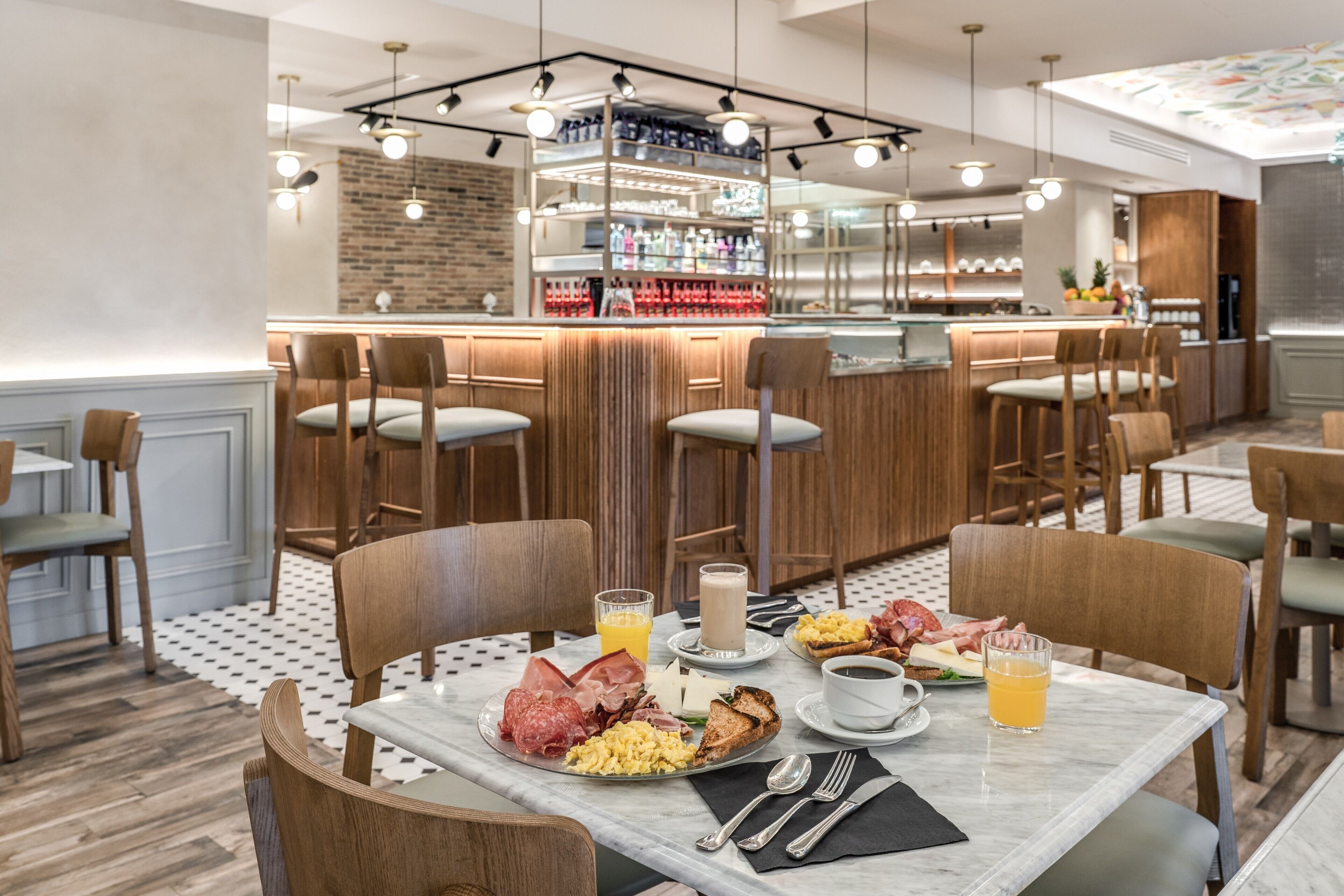 A breakfast setup with a variety of food items, bar area, and seating arrangement in a modern dining space.