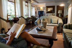 Una sala de estar acogedora con un sofá, una mesa de centro con libros y un televisor al fondo.