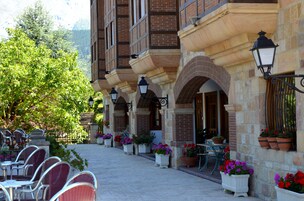 Un edificio con fachada de piedra, varias ventanas y mesas y sillas para disfrutar al aire libre.