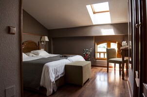 Un dormitorio con cama, mesita de noche, lámpara y vistas al exterior.