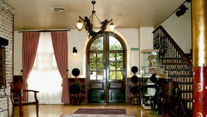 A spacious foyer with a large rug, a staircase, and a decorative chandelier. - Hotel El Jardín de la Abadía (Arroyo de la Encomienda)
