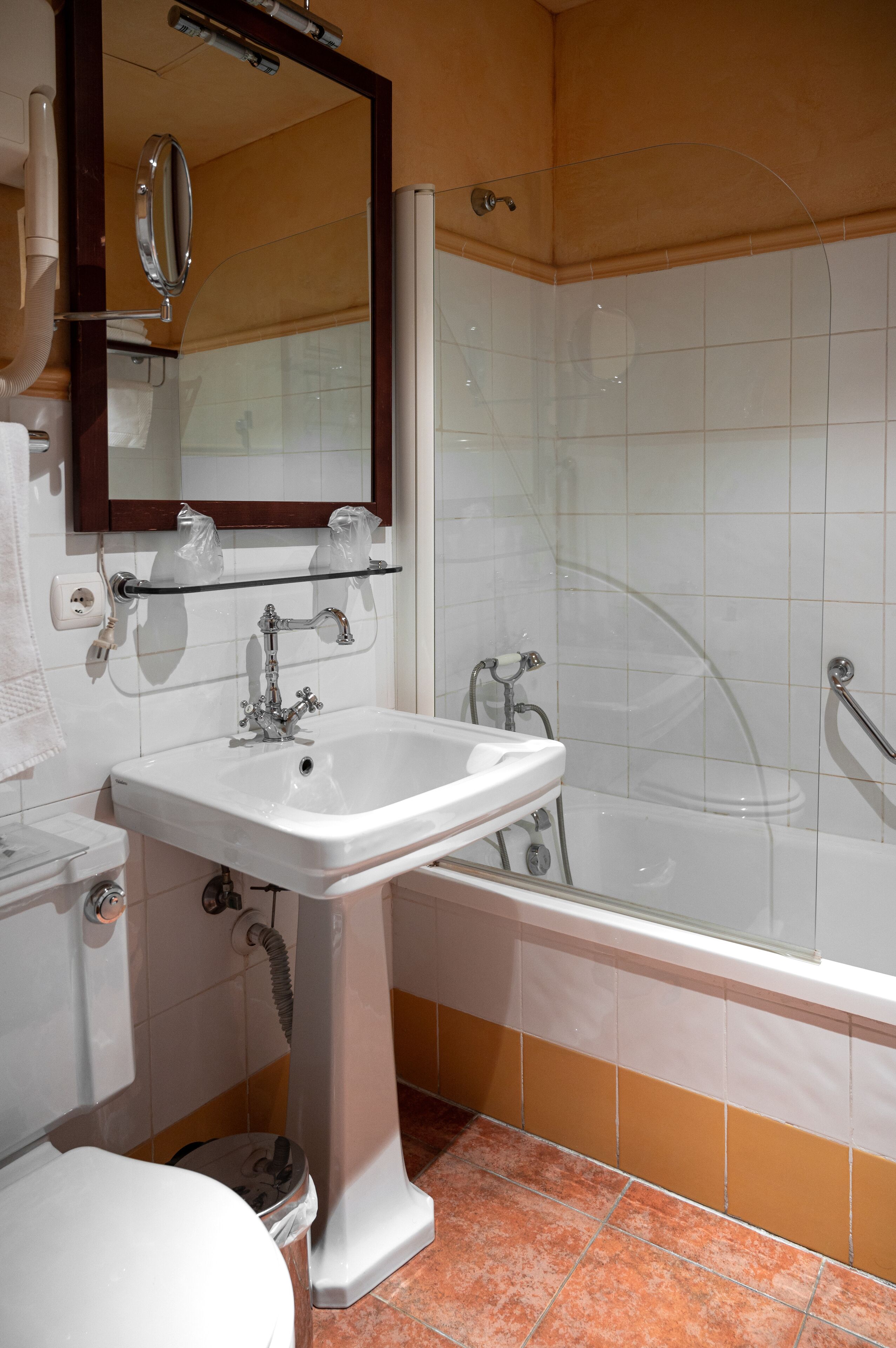 Une salle de bain avec un lavabo blanc, un miroir et une baignoire.