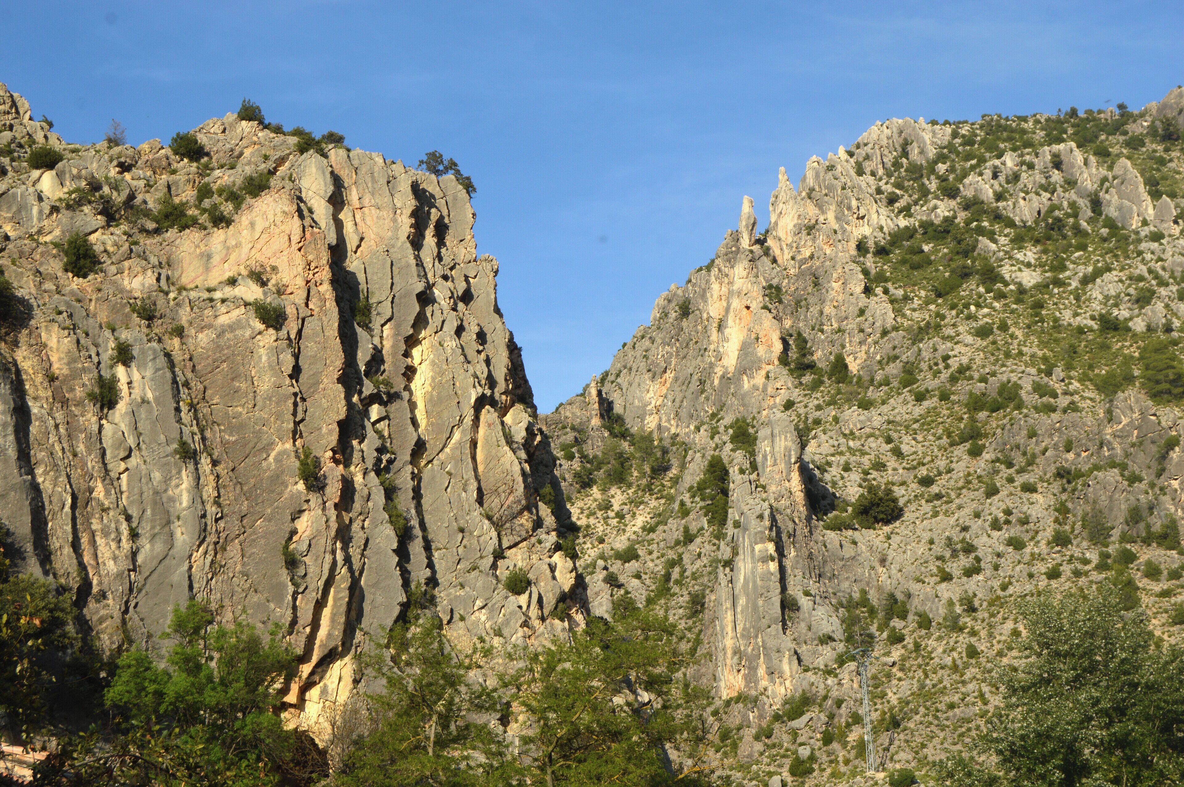 Un paisaje montañoso y agreste con acantilados rocosos y vegetación escasa.