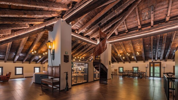 Un loft espacioso con vigas de madera a la vista, una escalera central y una zona de estar con chimenea.