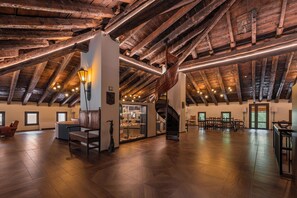 Un loft espacioso con vigas de madera a la vista, una escalera central y una zona de estar con chimenea.
