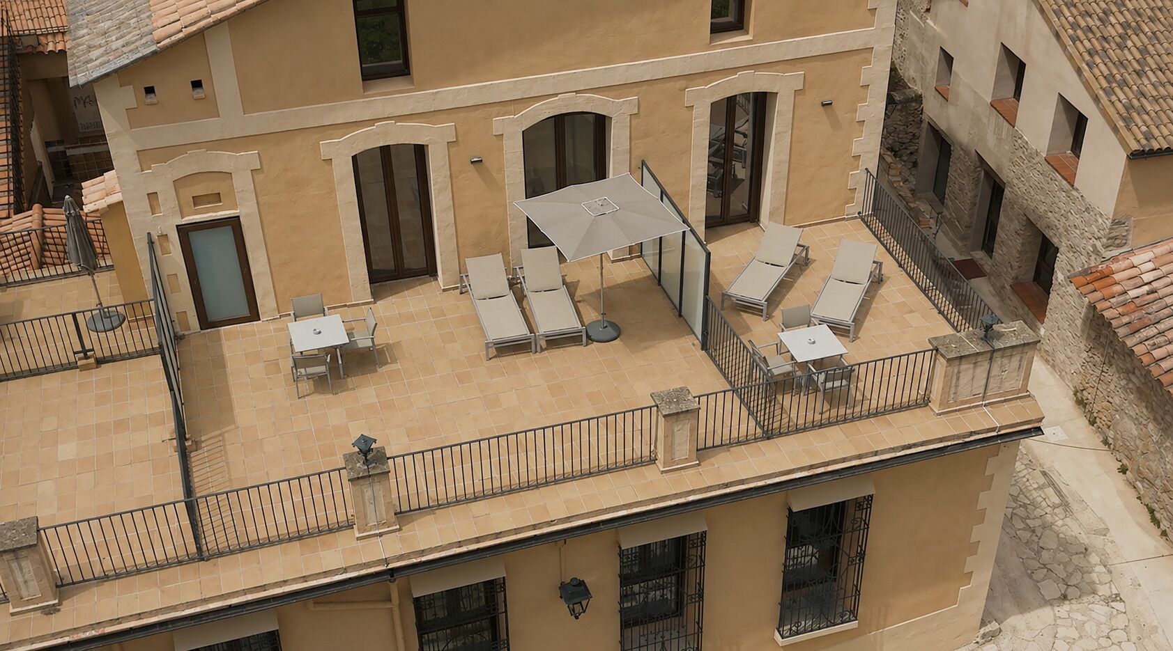 A rooftop terrace with outdoor seating, a covered area, and a stone wall.