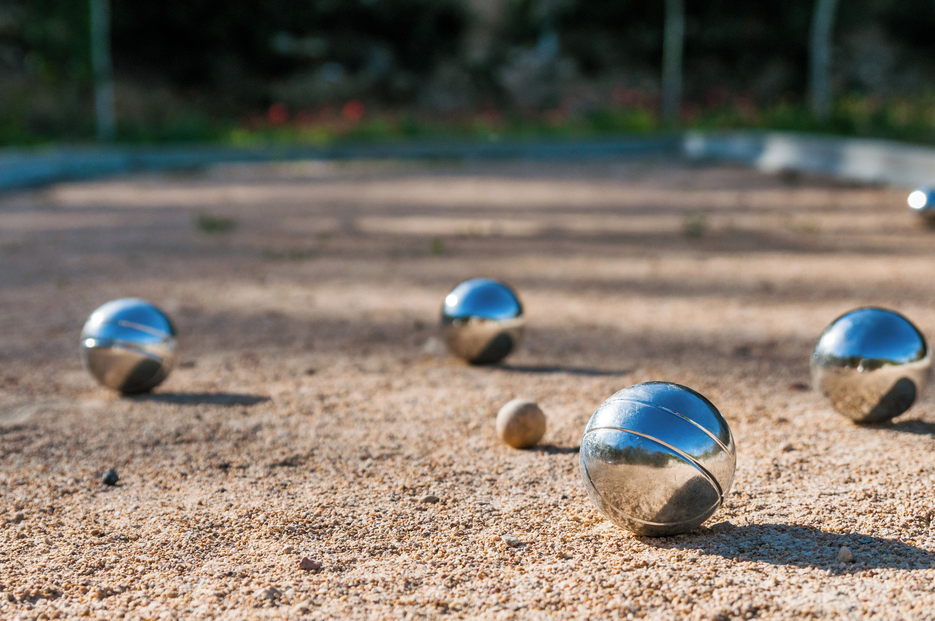 A close-up of shiny metallic spheres on a sandy surface.