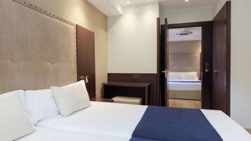 Habitación de hotel con una cama grande, mesitas de noche, un escritorio y un armario.