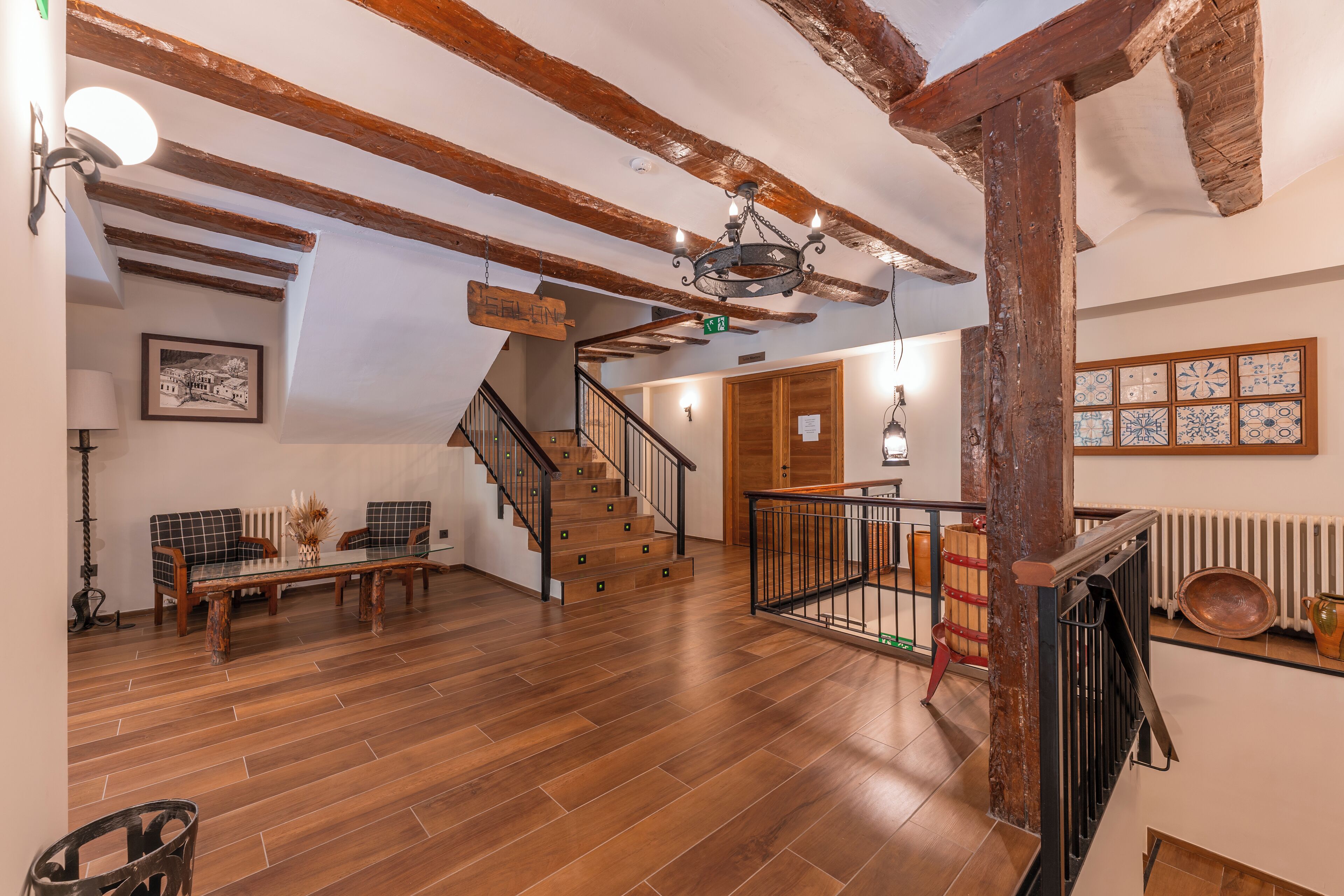 Amplia habitación con una escalera de madera, un comedor con mesa y sillas, y vistas al piso superior.