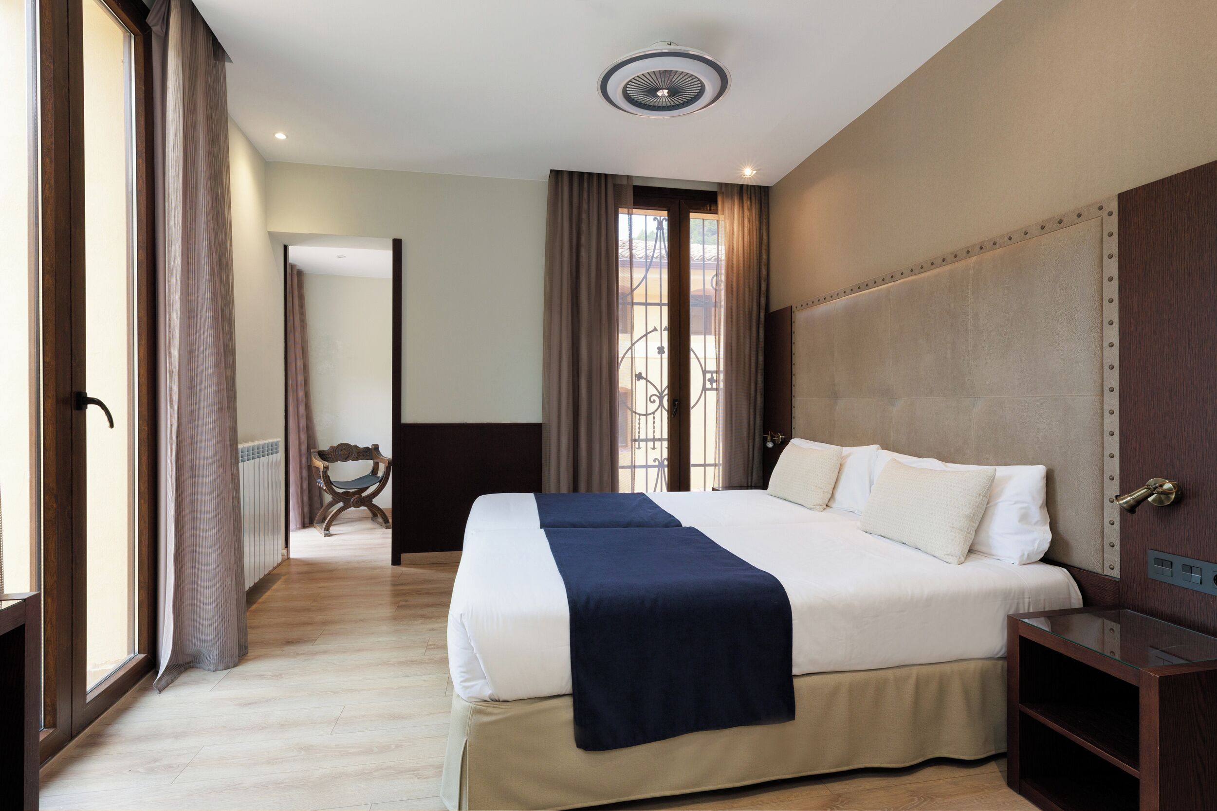 A hotel room with a large bed, a bedside table, a wardrobe, and a view through the window.
