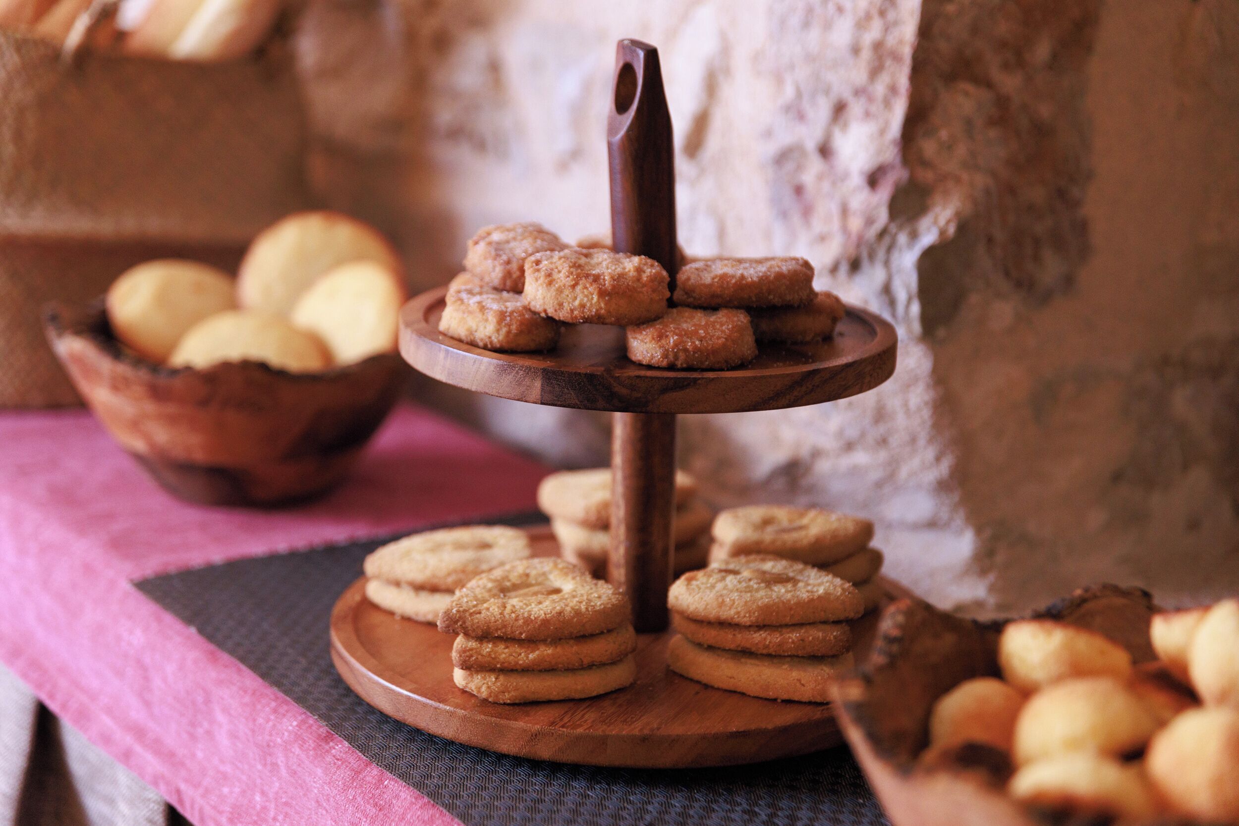 A wooden serving stand with cookies and a chocolate bar.