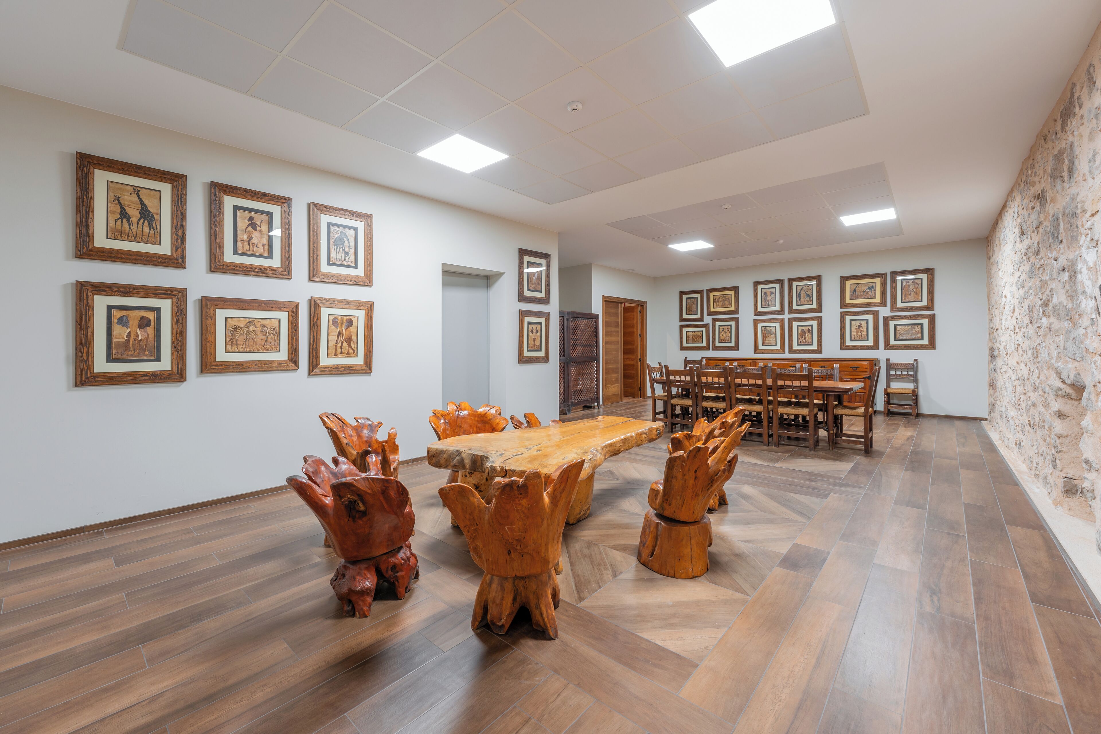Una habitación amplia con una gran mesa de madera y sillas, rodeada de cuadros en las paredes.
