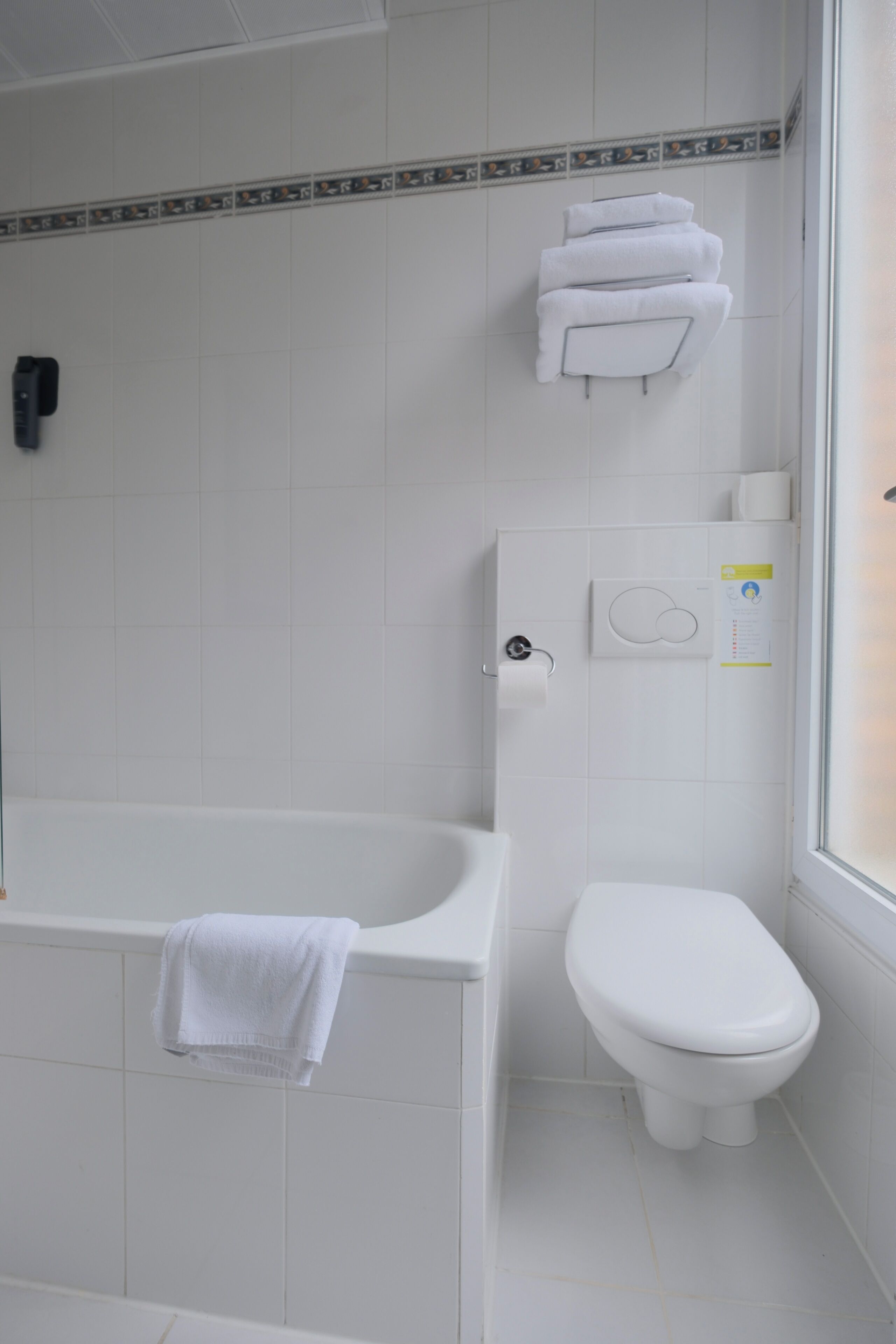 Un baño con bañera, inodoro y toallero.