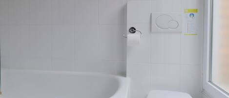 Un baño con bañera, inodoro y toallero.