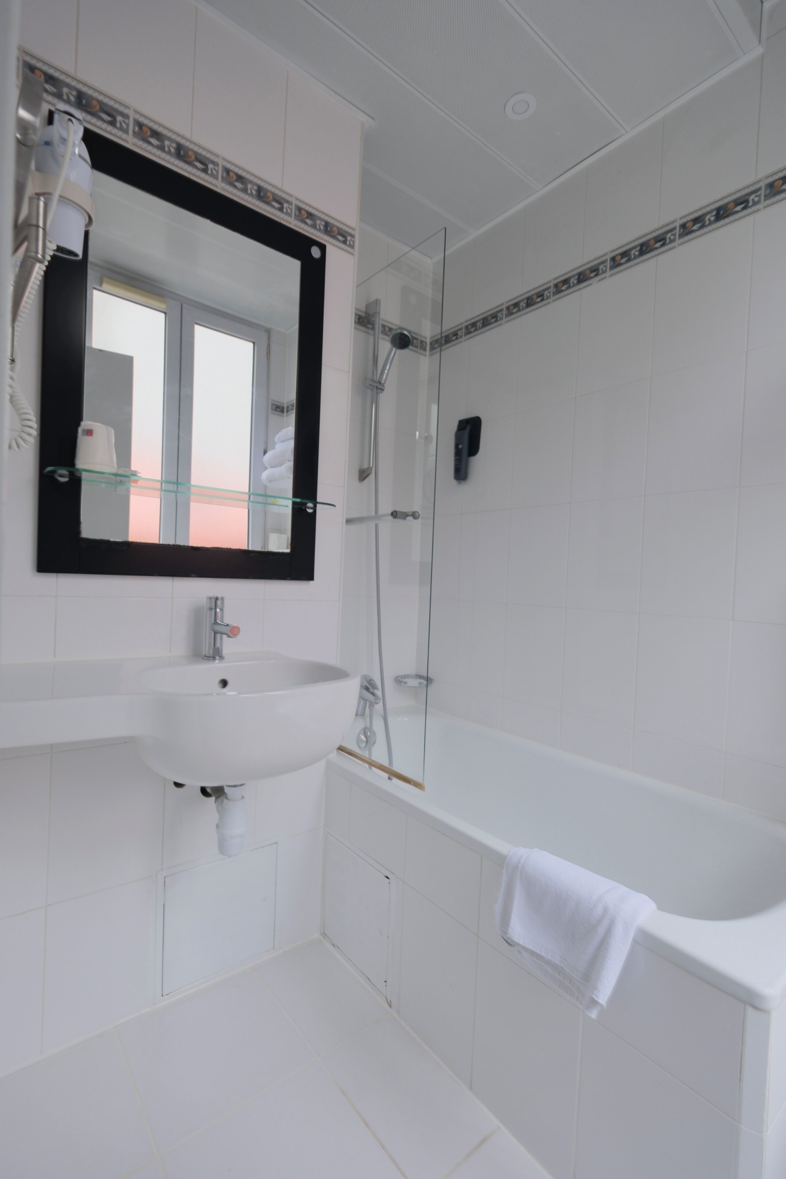 A modern bathroom with a white sink, mirror, and bathtub.