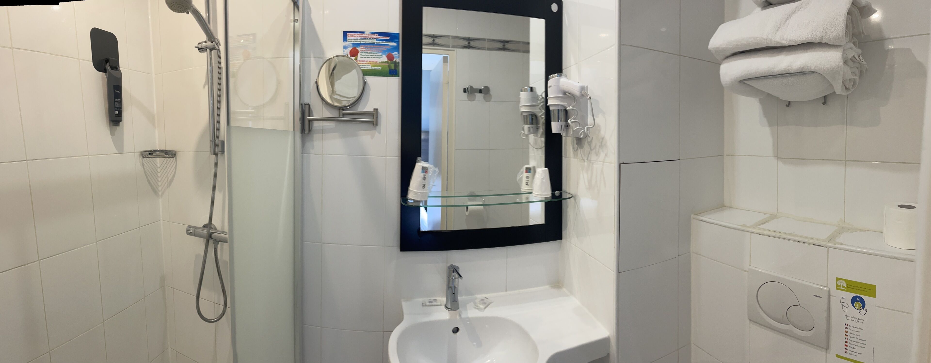 Een moderne badkamer met een douchecabine van glas, een wastafel, een spiegel en een handdoekrek.
