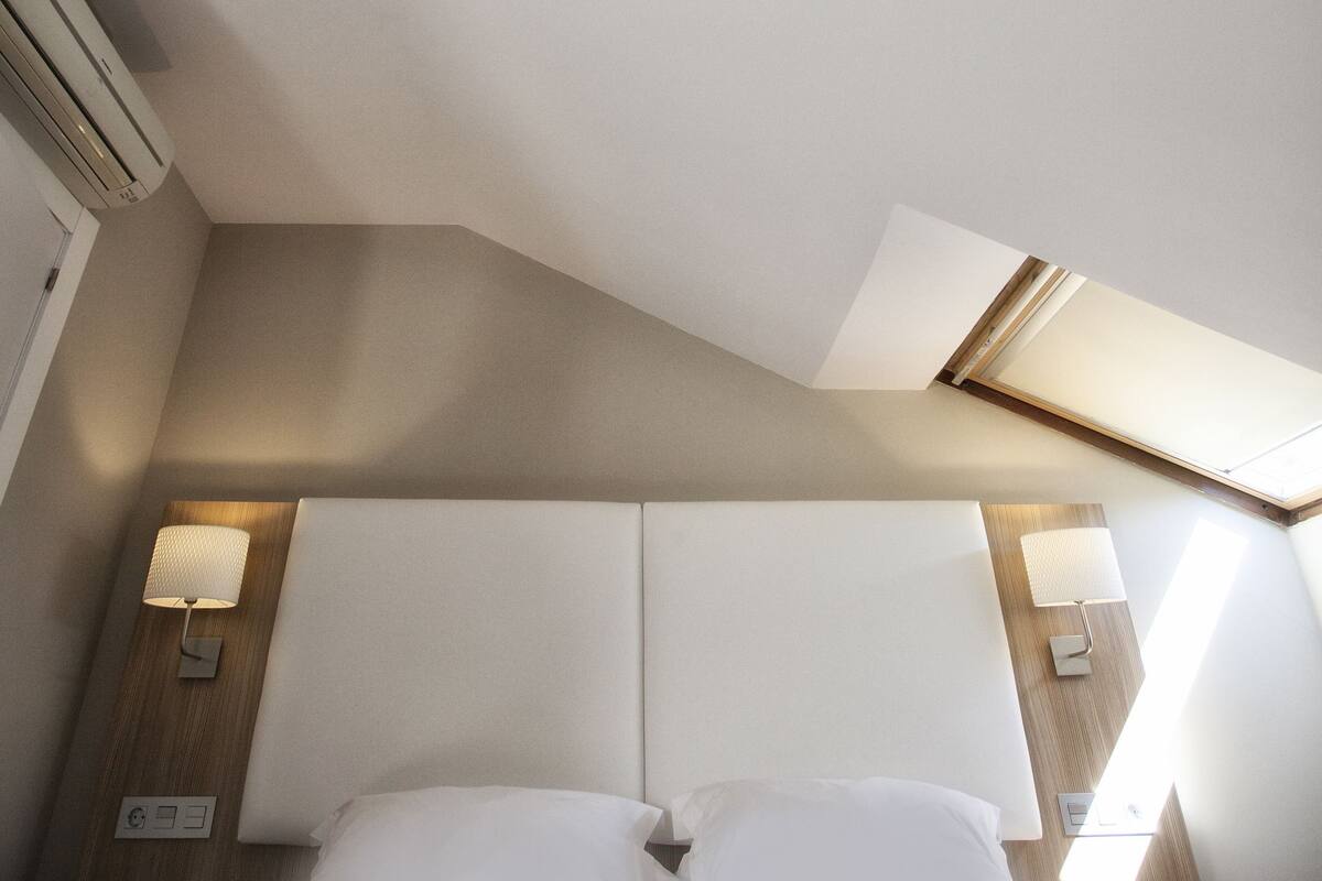Una habitación de hotel con una cama, una mesita de noche, una lámpara y un teléfono en la pared.