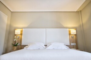 A hotel room with a large bed, two bedside lamps, and a small potted plant. - Hotel Los Lagos Nature (Cangas de Onis)