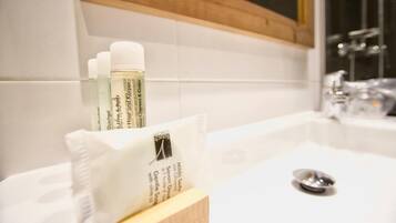 A bathroom with a white sink, a mirror, and toiletries including a bottle of soap and a pack of tissues.