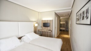 A hotel room with a large bed, a TV mounted on the wall, and a wooden floor.
