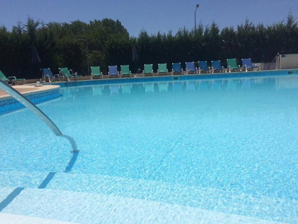 A clear blue pool with lounge chairs along the edge.