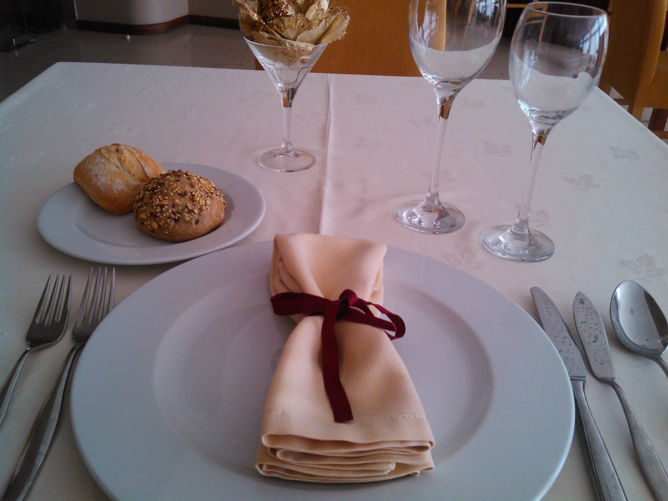 A table set with a folded napkin, two plates with food, and two wine glasses.