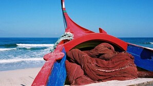 Un bateau à la coque rouge et bleue, amarré à un quai par une corde.
