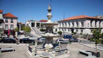 Una plaza pública con una fuente central, rodeada de edificios con tejados de tejas rojas.