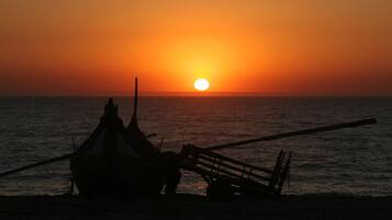 A boat silhouetted against a sunset on a calm sea.