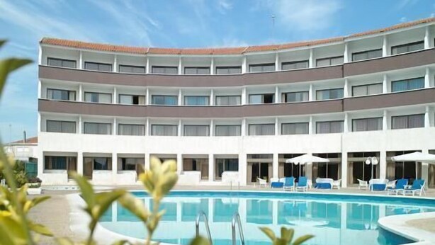 Un hôtel à plusieurs étages doté d’une piscine et de chaises longues.