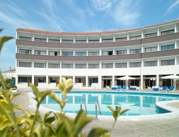 Una piscina al aire libre de temporada, sombrillas, tumbonas