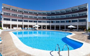 Una piscina al aire libre de temporada, sombrillas