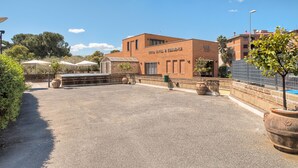 A hotel with a brick facade, outdoor seating area, and a clear sky. - Hotel Petra (Rome)