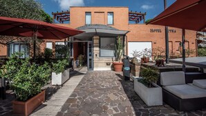 A hotel with a stone patio, outdoor seating, and a brick facade. - Hotel Petra (Rome)