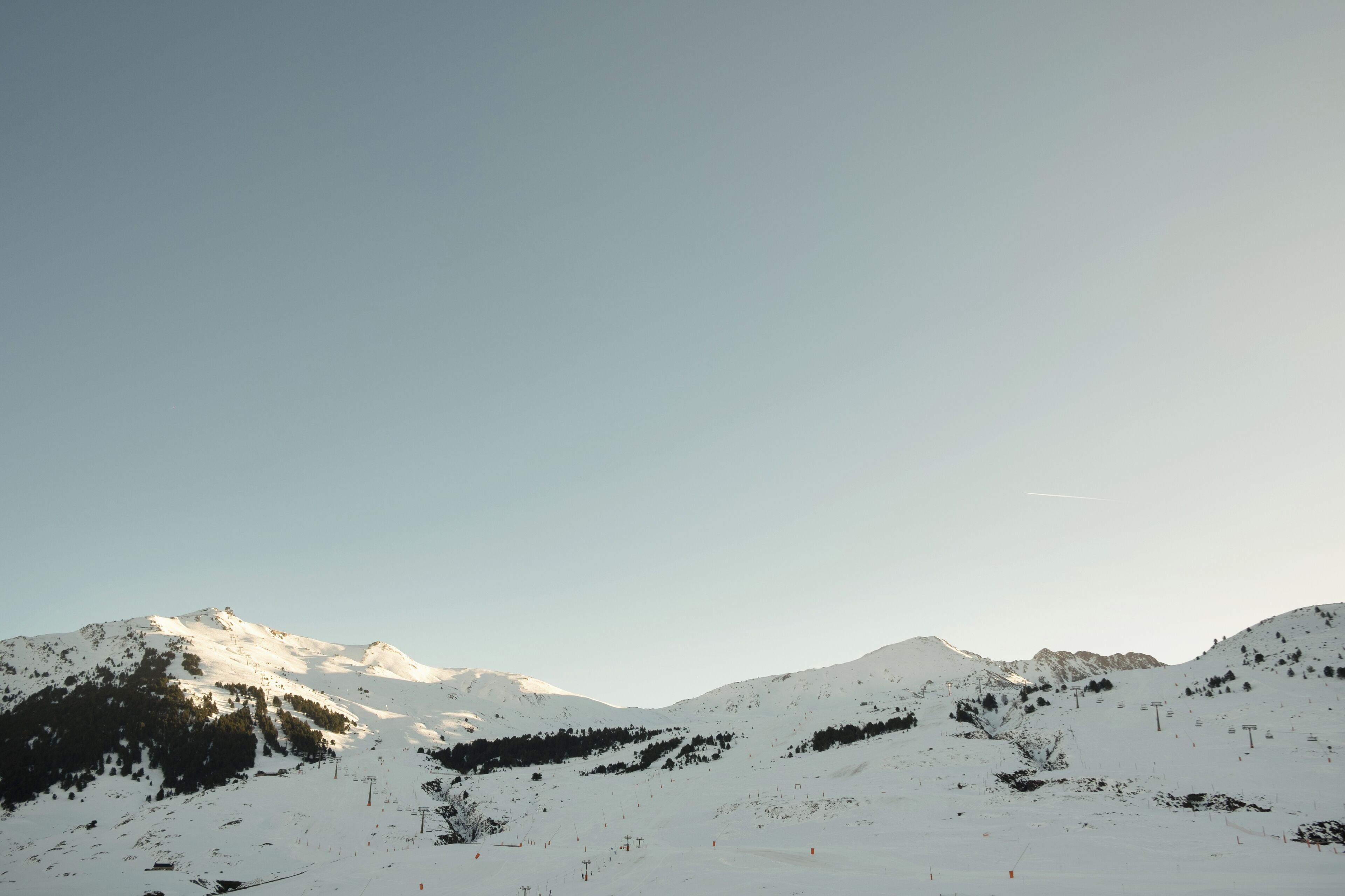 Un paisaje montañoso nevado con pistas de esquí y remontes.