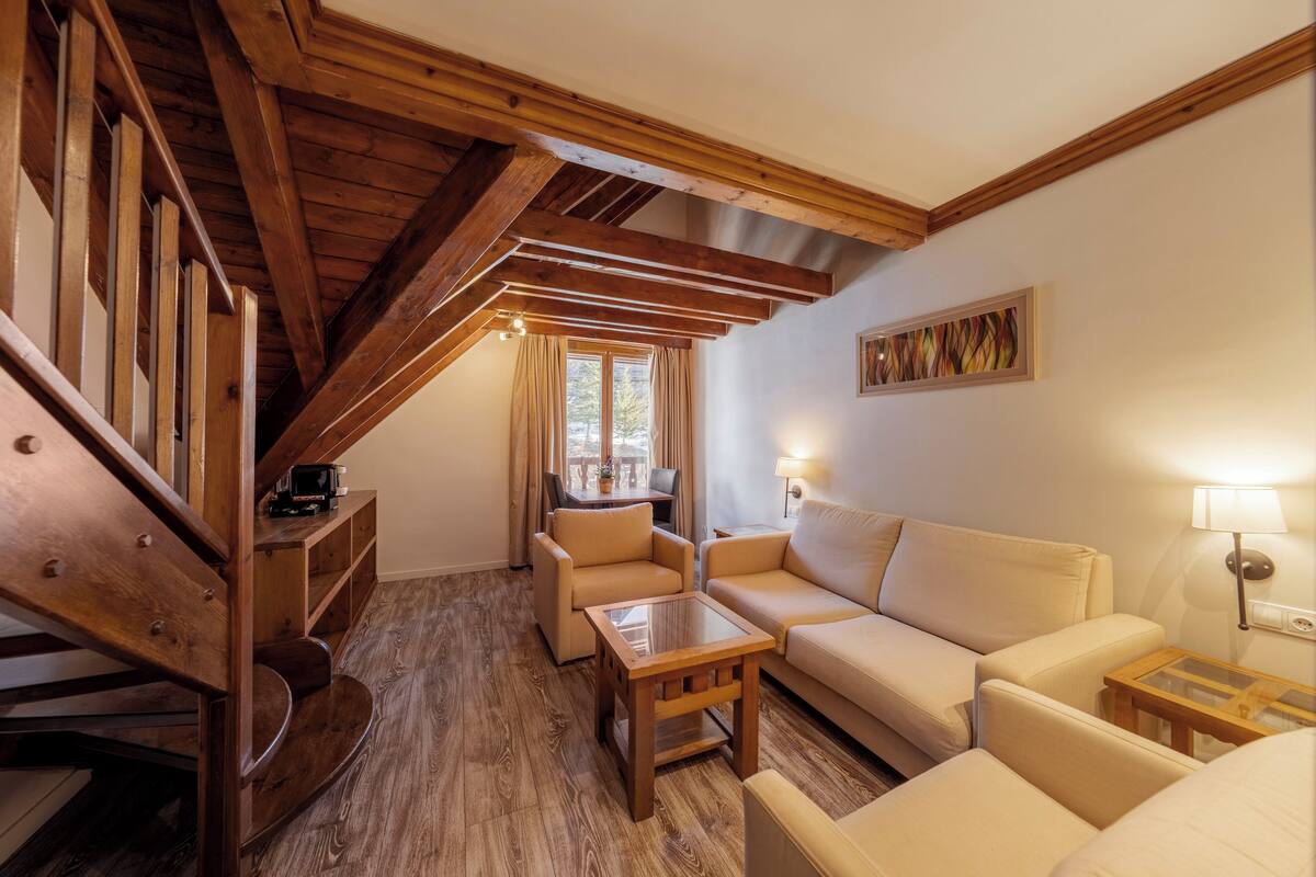 Un salon chaleureux avec un escalier en bois, un canapé, une table basse et un tableau accroché au mur.