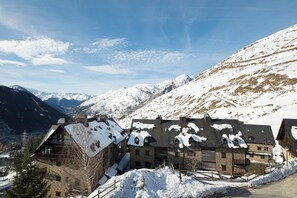 Un pueblo cubierto de nieve en la montaña, con casas de madera tradicionales, una carretera pavimentada y un cielo despejado.